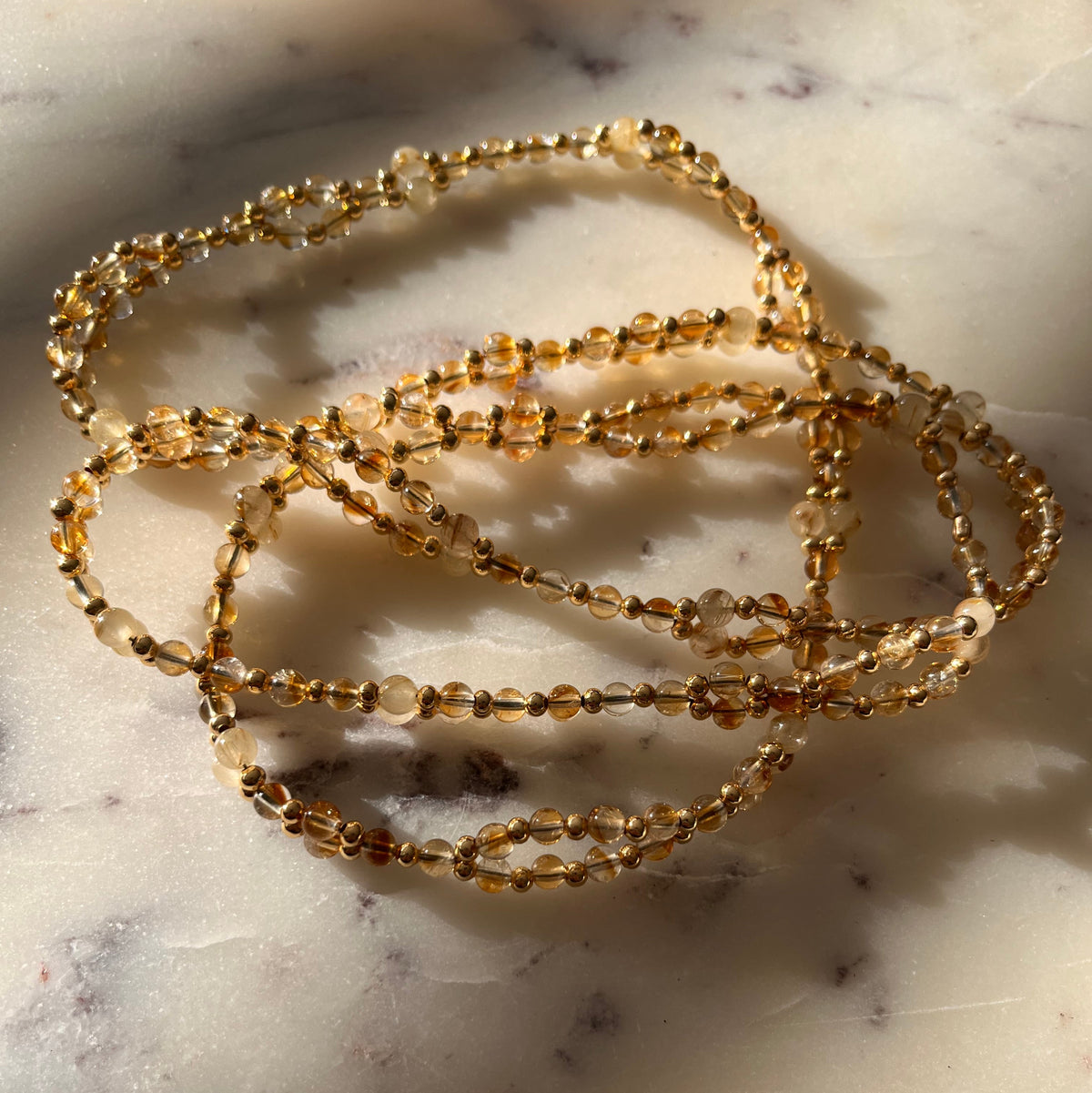 citrine and rutilated quartz on a marble slab, bathed in sunlight