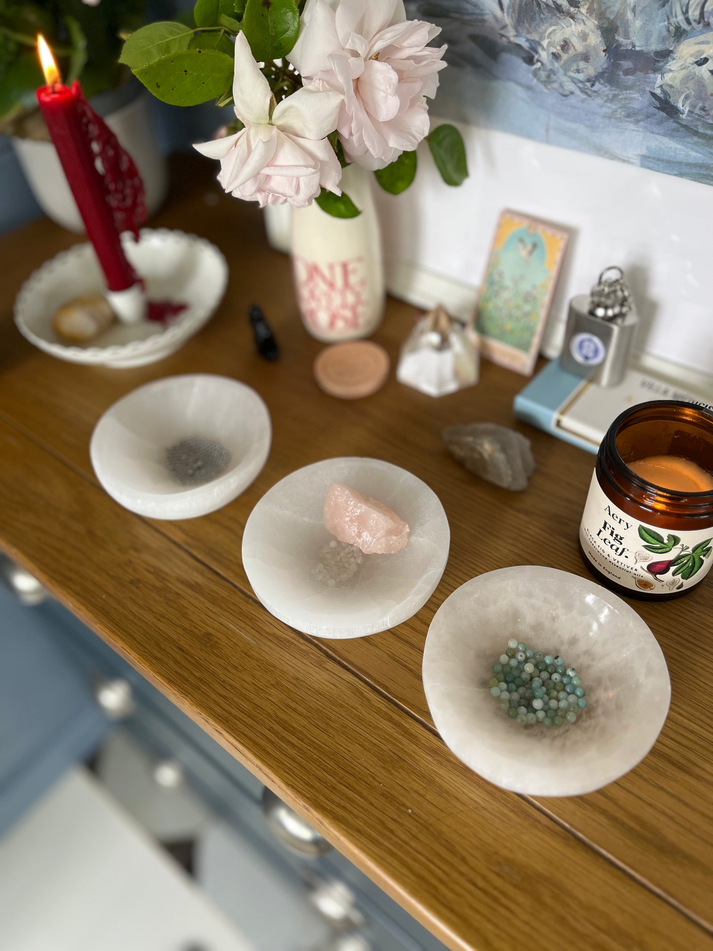 Amazonite and Rainbow Moonstone beads resting in a carved selenite bowl before being handcrafted into a sacred geometric tantric necklace, photographed on an altar.